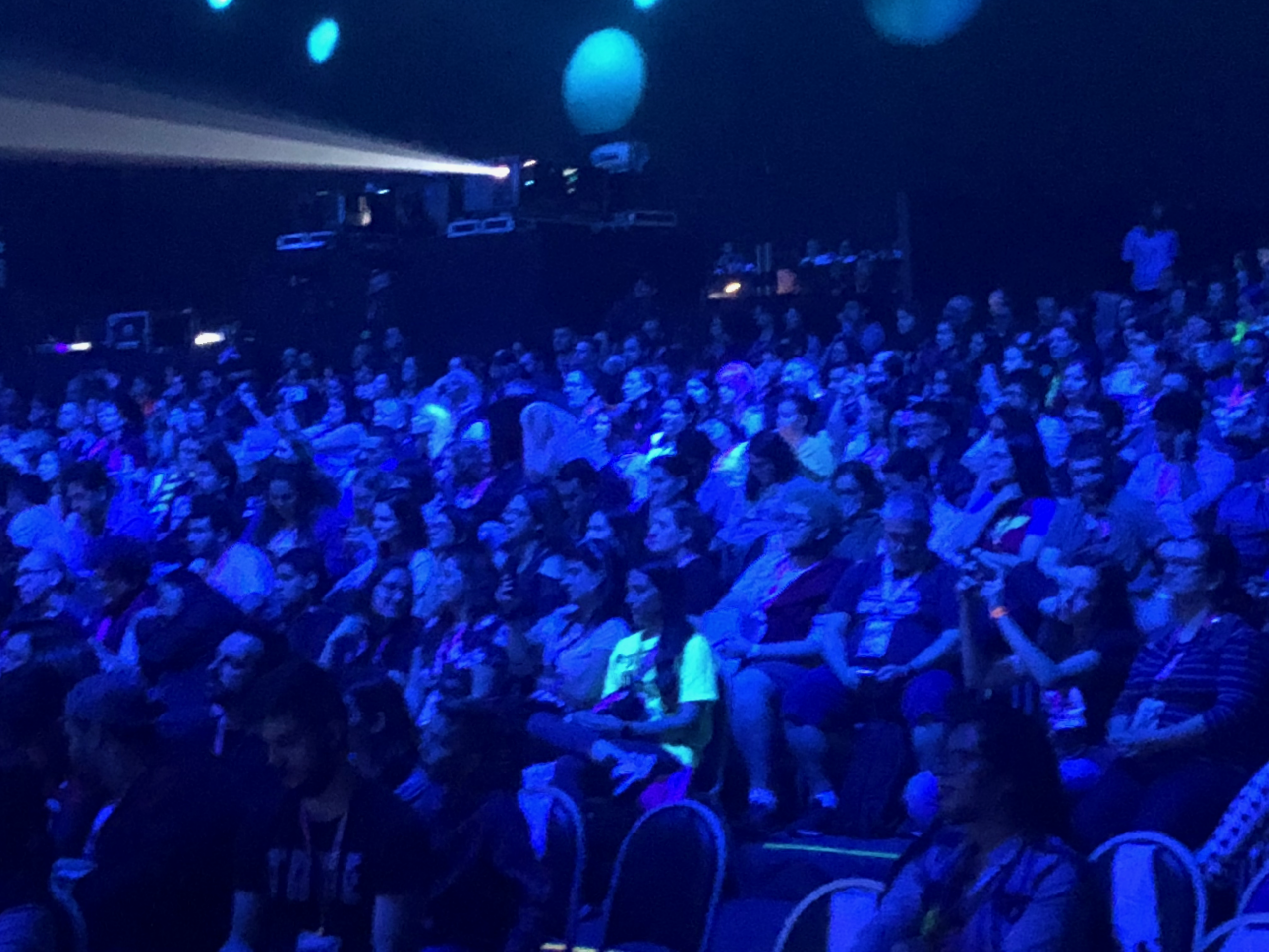 Audience bathed in blue light at a crowded event.